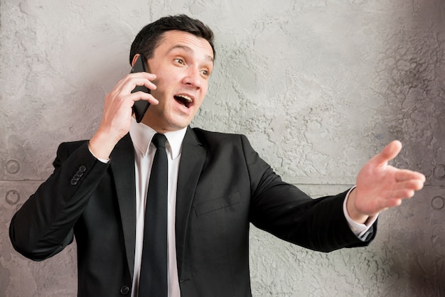 Excited businessman speaking on phone and pointing away