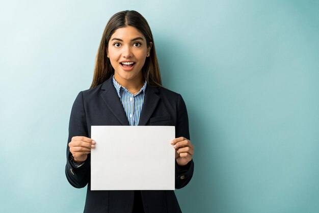 Excited businesswoman showing blank placard against blue background