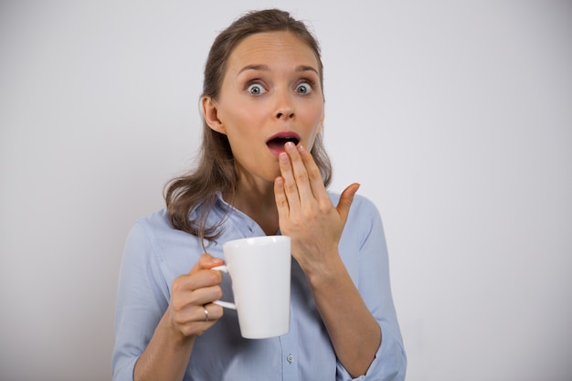 Excited businesswoman with mug shocked with news