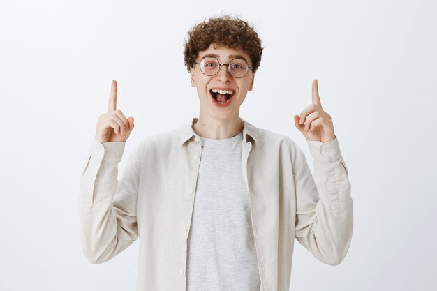 Excited carefree teenage guy posing against the white wall