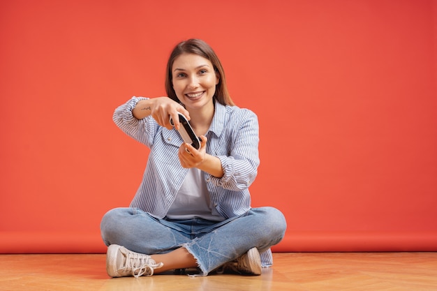 Excited casual young woman playing video games having fun on red