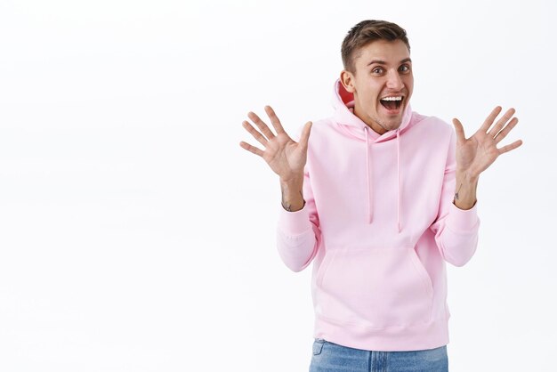 Excited cheerful man with blond hair make jazz hands waving palms in hello or hi gesture saying surprise as congratulating friend with pride month celebrating diversity white background