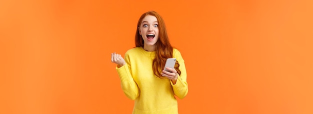 Free photo excited and cheerful redhead pretty female student got enrolled in exchange program learn news via o