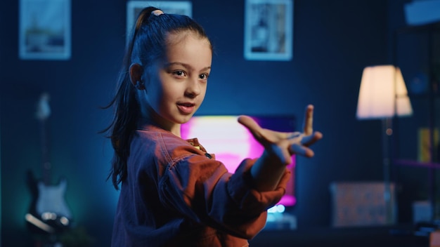 Free photo excited child doing viral dance choreography in apartment illuminated by neon lights