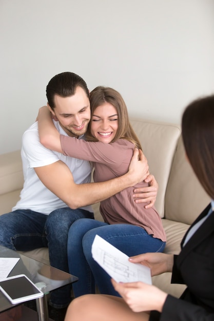 Возбужденные пары обнимаются на встрече с агентом по недвижимости, ипотечные инвестиции