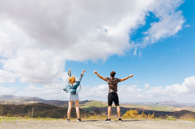 Excited couple with hands up on hilltop