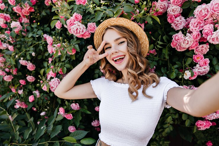 Free Photo excited curly girl in summer outfit making selfie. outdoor photo of romantic young woman having fun in garden.