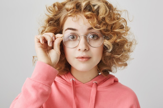 Excited curly-haired girl looking interested in glasses