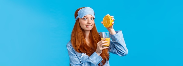 Free photo excited and cute pretty caucasian redhead woman in pyjama and sleep mask biting lip tempting and eag