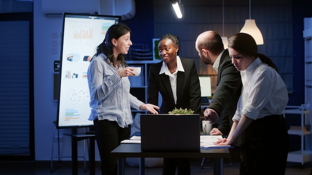 Eccitato lavoro di squadra diversificato che riceve buone notizie applaudendo stando in piedi al tavolo