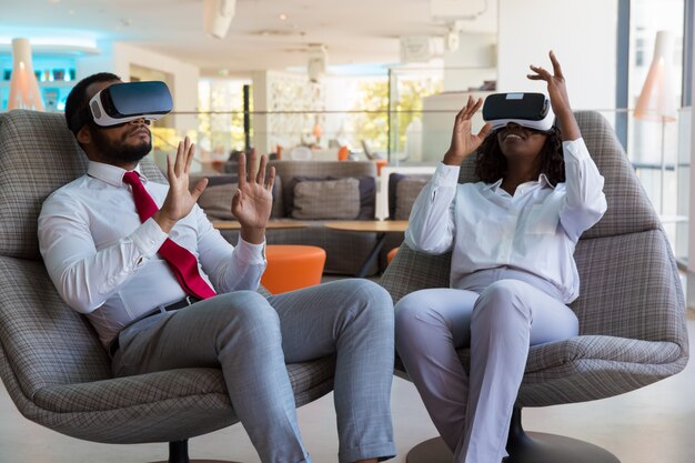 Волнующие разнообразные коллеги в очках виртуальной реальности играют в виртуальную игру