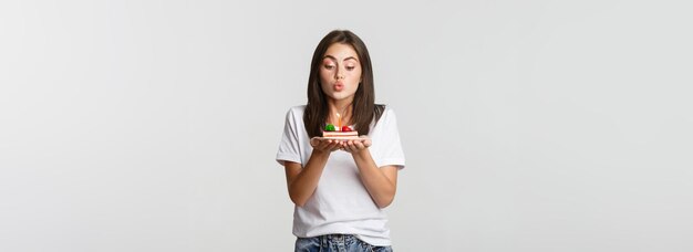 ろうそくを吹くバースデー ケーキに願いを作る興奮して夢のようなかわいい誕生日の女の子