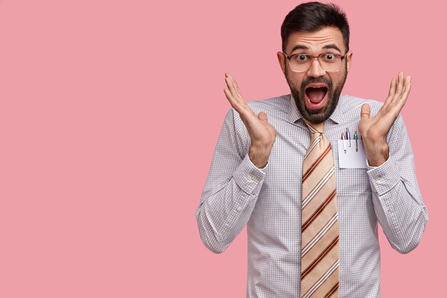 Excited emotive businessman gestures actively keeps mouth opened