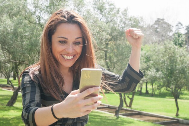 Excited euphoric lady with smartphone celebrating great news