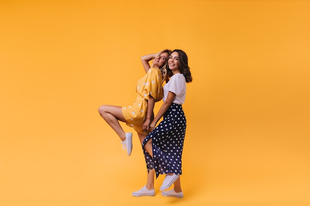 Excited fair-haired young lady having fun with best friend. Adorable european sisters expressing positive emotions.