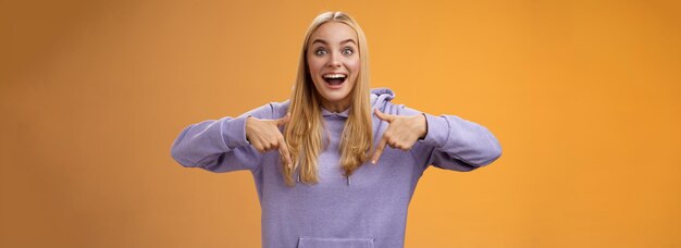 Free photo excited fascinated european cute young girl blond hair smiling open mouth amused telling look down