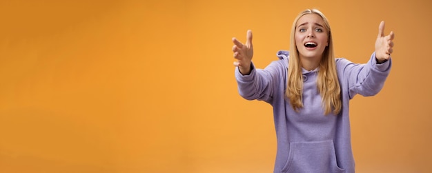 Free photo excited fascinated glad blond woman adore singer performing stage extend arms forward reaching