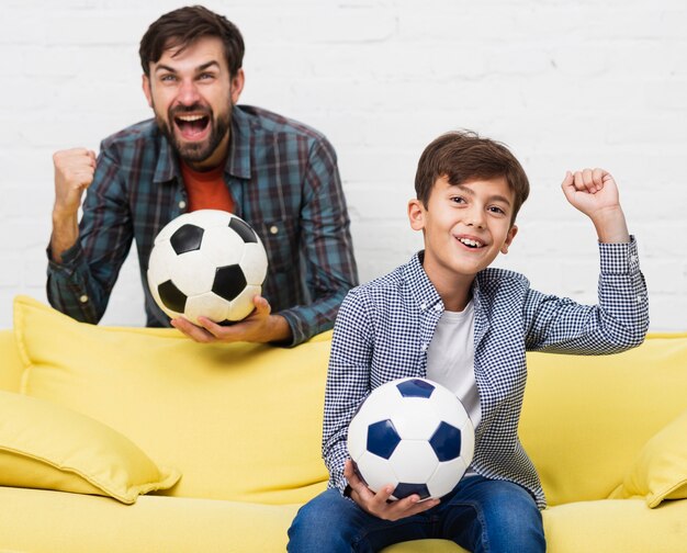 興奮して父と息子のサッカーの試合を見て 無料の写真