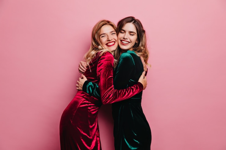 Free Photo excited female friends huggs on pink wall. indoor photo of blithesome adult sisters posing with smile.