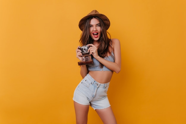 Excited female photographer standing in confident pose on yellow space