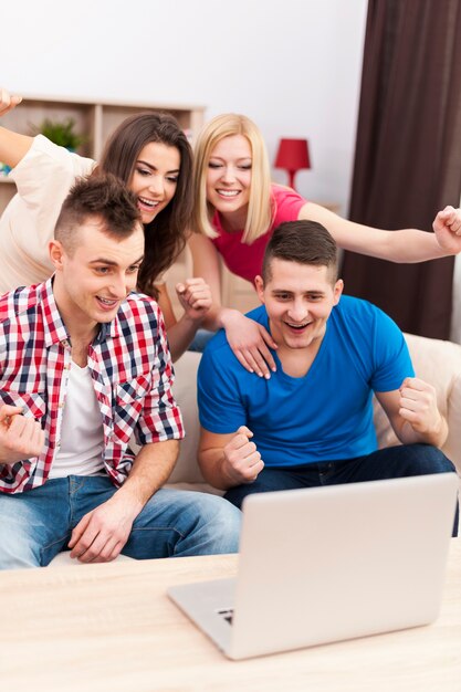 Excited friends watching soccer match on laptop