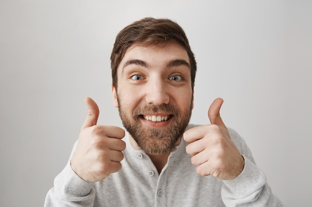 Excited funny bearded guy showing thumbs-up in approval