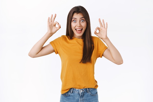 Excited, funny cheerful woman look wild and amused, widen eyes thrilled showing okay, ok gesture with amazement, impressed with excellent band performance, recommend event everyone, white background