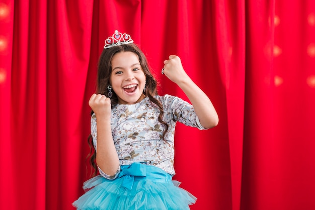 Excited girl standing in front of red curtain