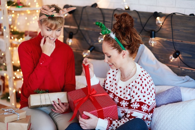 ベッドでクリスマスプレゼントを開く興奮した女の子