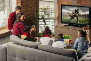 Free photo excited group of people watching american football, sport match at home.