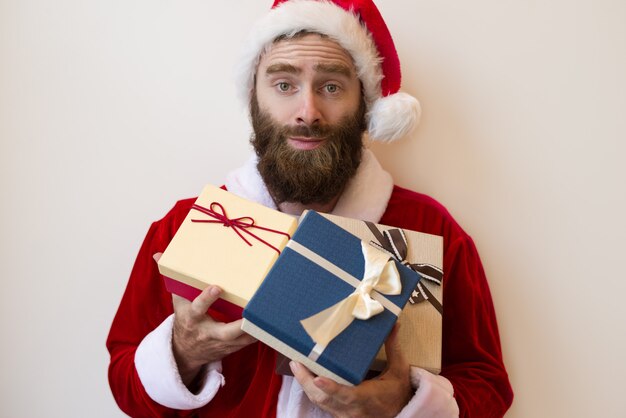 Excited guy wearing Santa costume and holding gift boxes