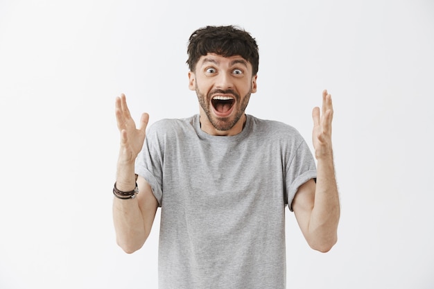 Excited handsome guy posing against the white wall