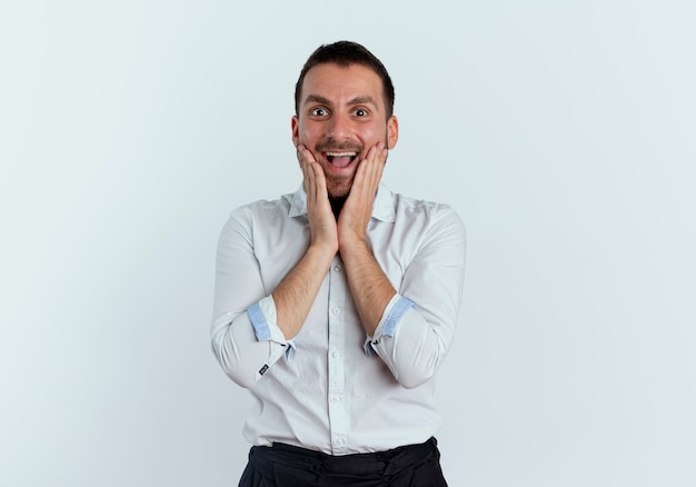 Excited handsome man puts hands on face isolated on white wall