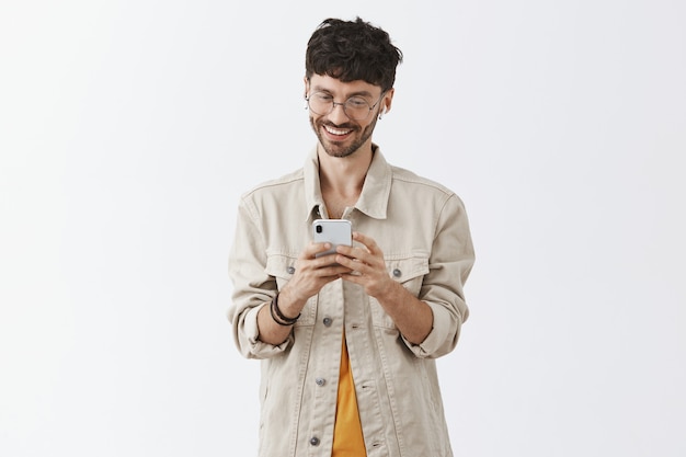 Free photo excited handsome young man using mobile phone and looking happy