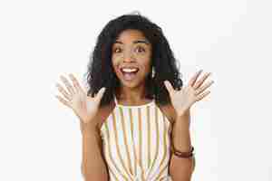 Free photo excited happy and expressive attractive african american woman with curly hairstyle raising palms