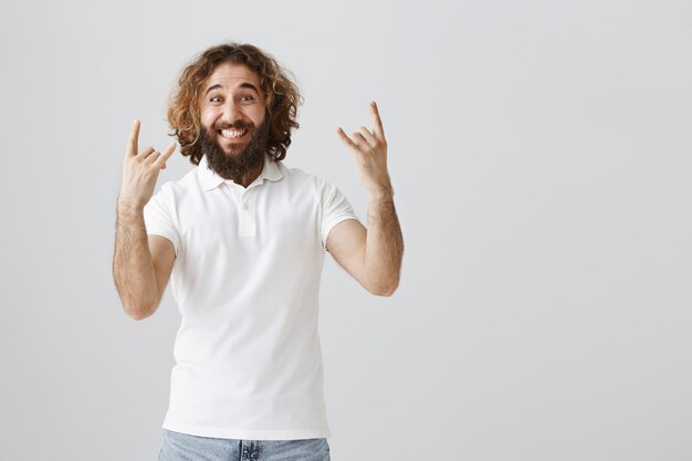 Взволнованный и счастливый человек с Ближнего Востока, показывающий рок-н-ролльный жест, веселится