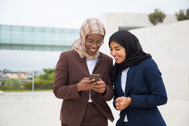 Excited happy office employees looking at smartphone