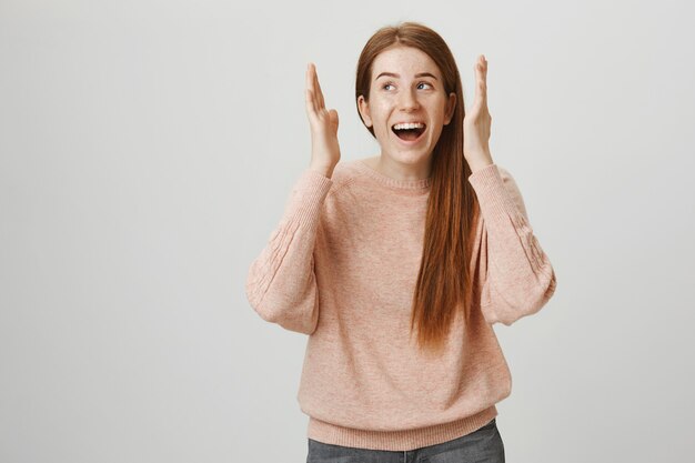 Ragazza rossa emozionante felice apre gli occhi e distoglie lo sguardo entusiasta