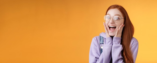 Free photo excited happy smiling broadly redhead girlfriend drop jaw grinning thrilled look left astonished