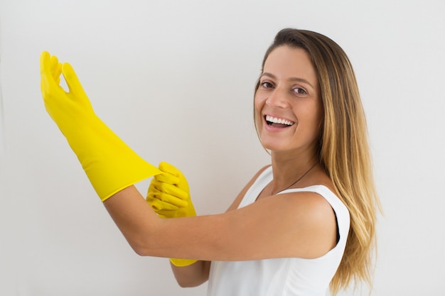 Free photo excited housewife putting rubber glove on hand