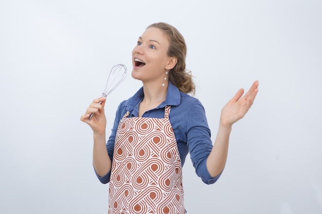 Excited housewife using whisk as microphone