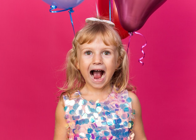 복사 공간 핑크 벽에 고립 된 헬륨 풍선으로 서 흥분된 작은 금발 소녀