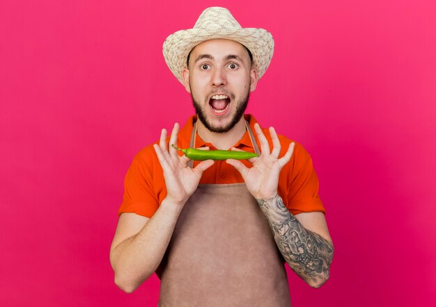 Foto gratuita il giardiniere maschio emozionante che porta il cappello di giardinaggio tiene il peperoncino piccante