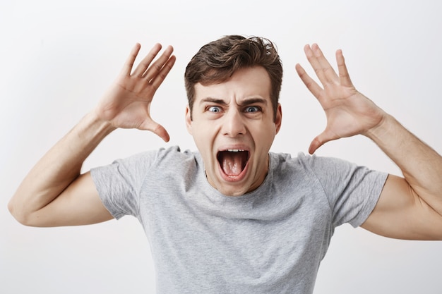 Excited male model dressed casually stares  with unbelievable gaze, screaming in surprise to recieve unexcpected news from relatives. People, facial expressions, emotions concept