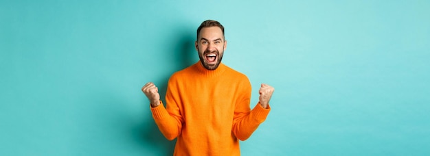 Excited man celebrating victory rejoicing and making fist pump gesture winning and looking satisfied