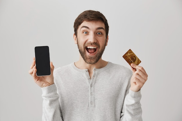 온라인 주문, 신용 카드 및 휴대 전화 화면을 보여주는 흥분된 남자