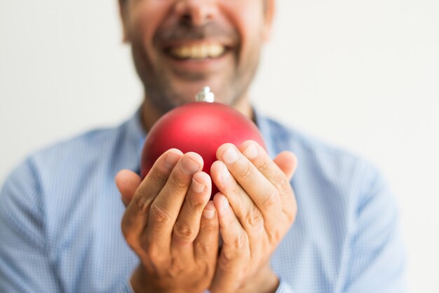 Excited man making wish while holding red bauble in hands