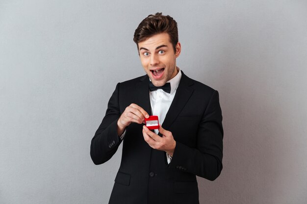 Возбужденный мужчина в официальном костюме держит коробку с предложением кольцо.
