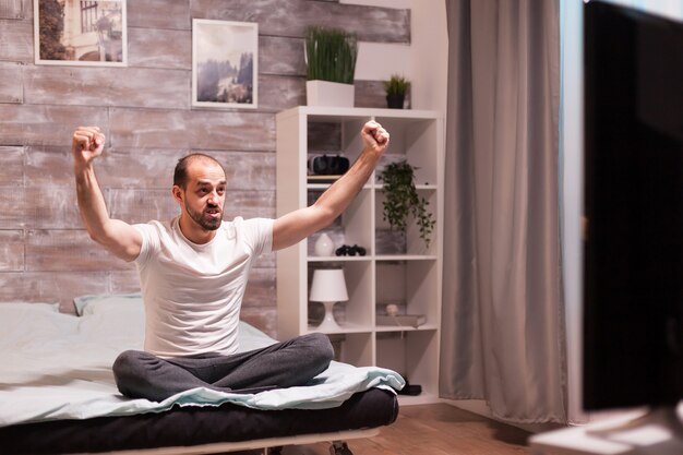 Free photo excited man watching a football match at night on big tv.