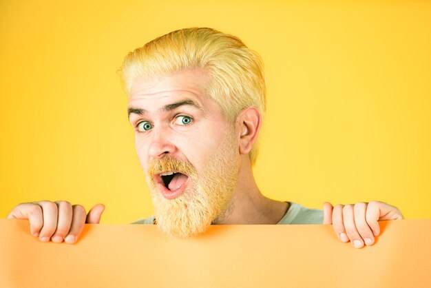 Excited man with blank sheet paper blank empty paper billboard with copy space for text